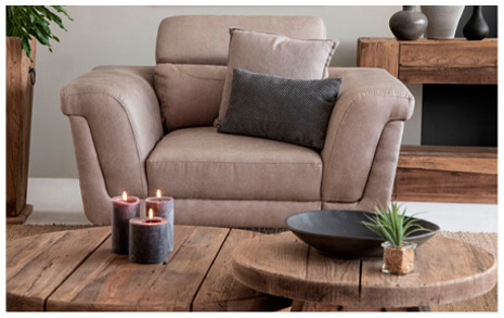Front view of rustic living room interior showing sandstone one seater couch and two round coffee tables with decorative accessories on top of it